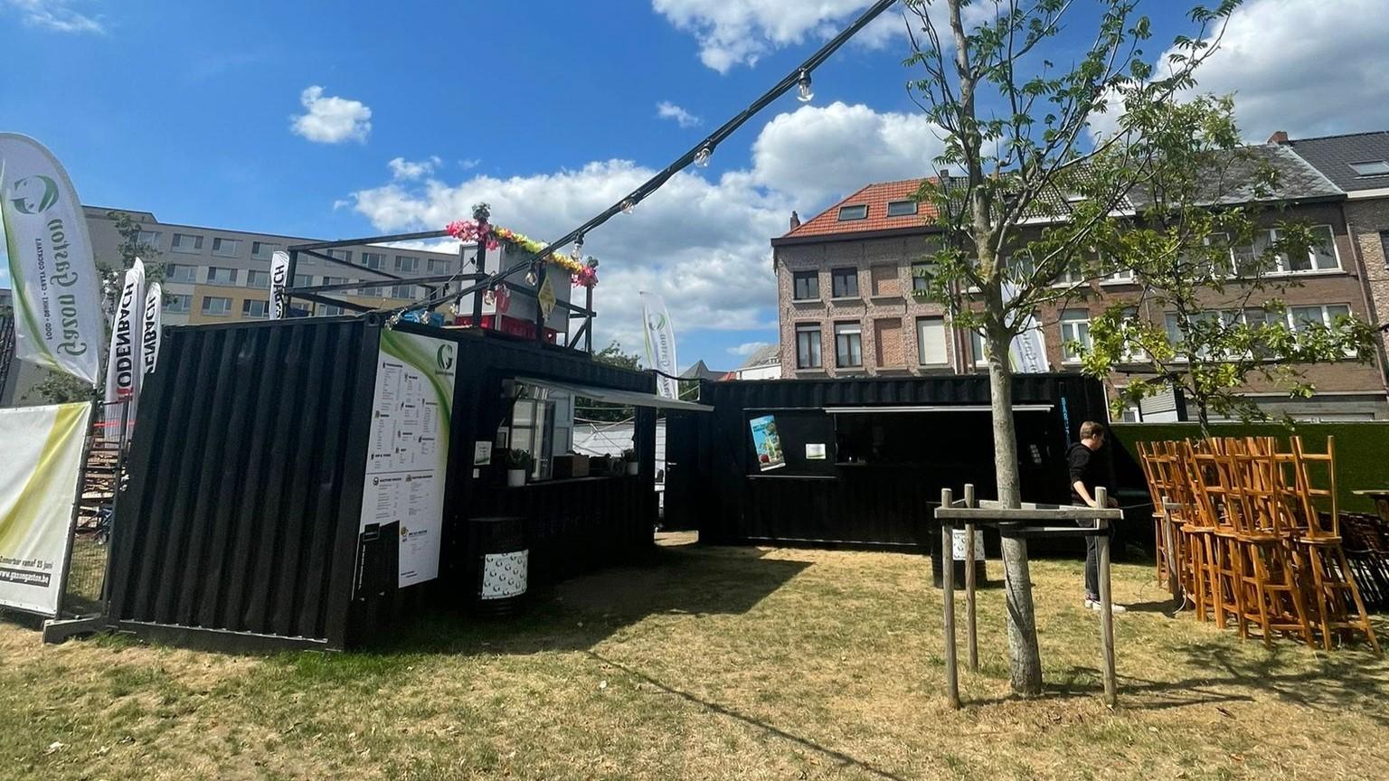 Two Pop up single hatch black 20 foot bar container on grass with custom lights for summer drinks in Mechelen. Available for sale or rent at ContainerID